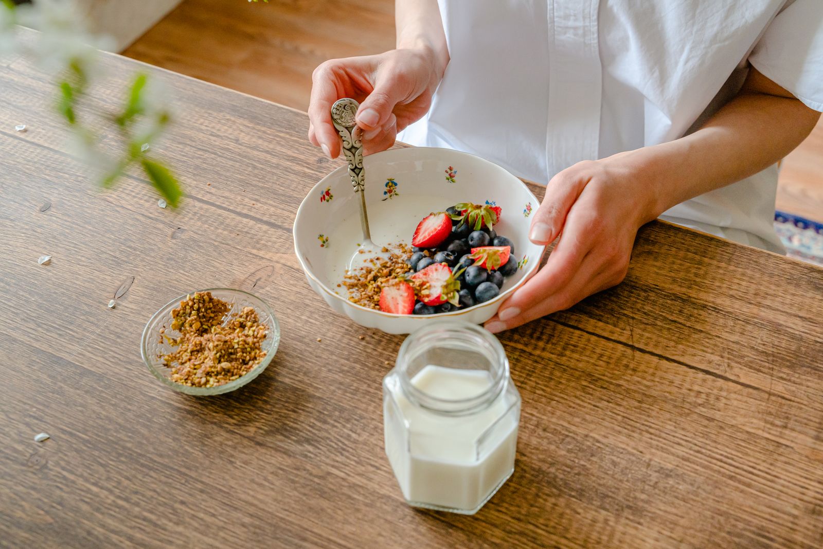 Kom yoghurt met bessen en noten naast twee groene dumbbells